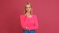 Pond5 Attractive young woman blonde in a red t-shirt and jeans posing on a pink