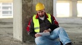 Builder With Tablet Computer Sits On The Floor