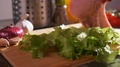 Close-Up View Of Human Hand Putting A Fresh Beefsteak On A Board With Lettuce