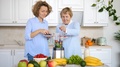 Granddaughter And Grandmother Preparing Fresh Vegan Smoothie On Kitchen