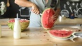 Male Holding In Hands And Cutting Juicy Watermelon At Modern Kitchen.